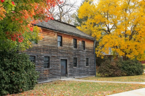 A rustic wooden building surrounded by vibrant autumn foliage in shades of red and yellow.