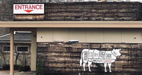 Signage on a building featuring "ENTRANCE" and a cow graphic labeling different cuts of meat.