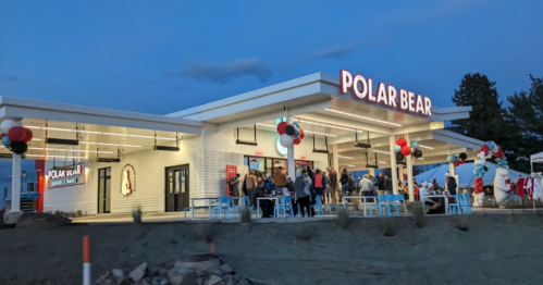 A lively ice cream shop named "Polar Bear" with outdoor seating, colorful balloons, and a crowd enjoying the evening.