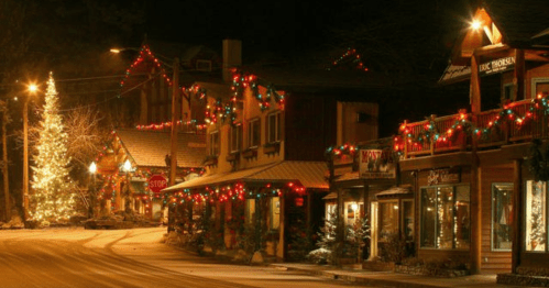 A festive street at night, adorned with colorful Christmas lights and a decorated tree, creating a cozy holiday atmosphere.