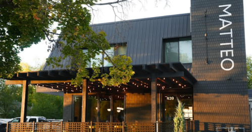 Modern restaurant exterior with a sign reading "MATTEO," featuring outdoor seating and string lights.