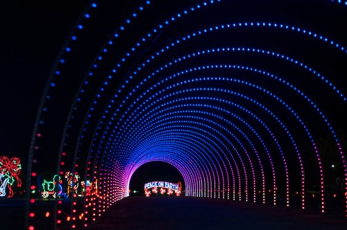 A colorful light tunnel with blue and pink lights, leading to a sign that reads "Peace on Earth."