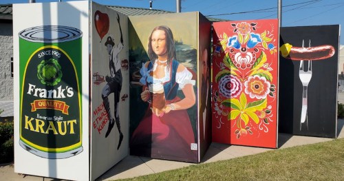 Colorful murals on large panels featuring a can of kraut, a woman in traditional dress, and vibrant floral designs.