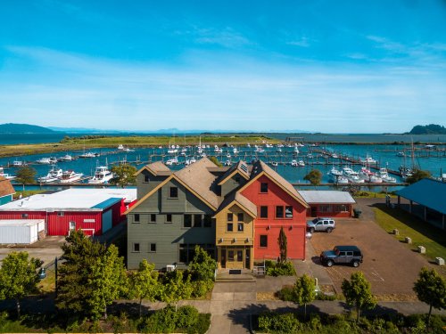 A colorful building overlooks a marina filled with boats, surrounded by greenery and a clear blue sky.