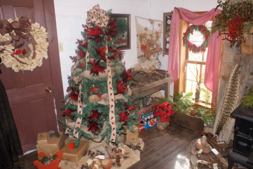 A cozy room decorated for the holidays, featuring a Christmas tree, gifts, and festive decor on the walls.