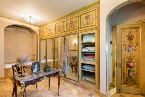 Elegant dressing room featuring ornate cabinetry, a vintage dress, and decorative details on the walls and door.