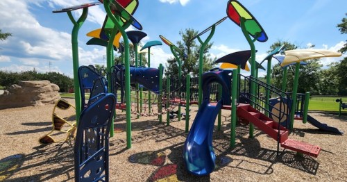 Colorful playground equipment with slides and climbing structures under a bright blue sky.