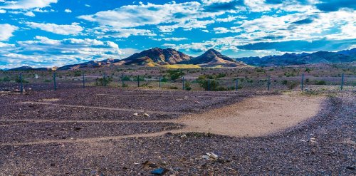A vast desert landscape with mountains in the background and a blue sky filled with clouds.