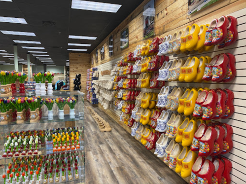 A store display featuring colorful wooden clogs on a wall, with tulip decorations in the foreground.
