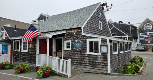 A quaint seafood restaurant with a shingled exterior, featuring an "Open" sign and American flag outside.