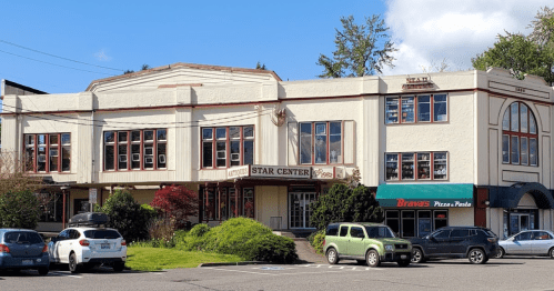 Historic building with "Star Center" signage, featuring shops below and parked cars in front. Clear blue sky above.