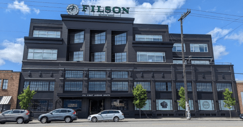 A large black building with "Filson" signage, featuring large windows and parked cars in front.