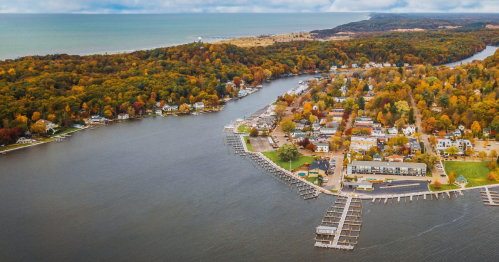 Aerial view of a river winding through a colorful autumn landscape with homes and docks along the shore.