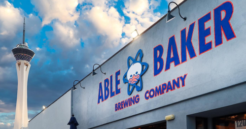 Exterior of Able Baker Brewing Company with a cloudy sky and the Stratosphere Tower in the background.