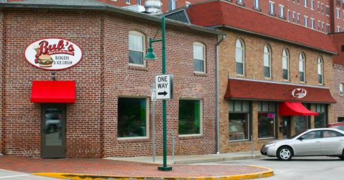 A brick building with red awnings, featuring signs for "Bob's Burgers & Ice Cream" and a nearby one-way street sign.