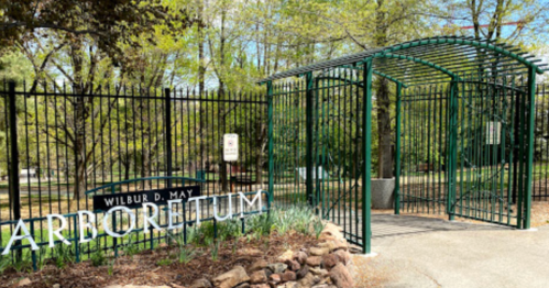 Entrance gate to Wilbur D. May Arboretum, surrounded by greenery and trees on a sunny day.
