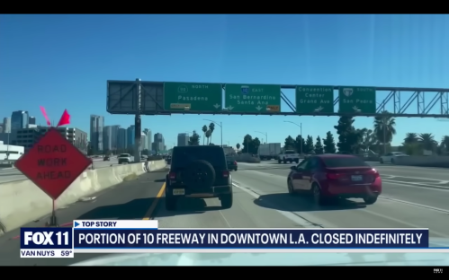 Traffic on a freeway in downtown L.A. with a road work sign and closed lane indicators.