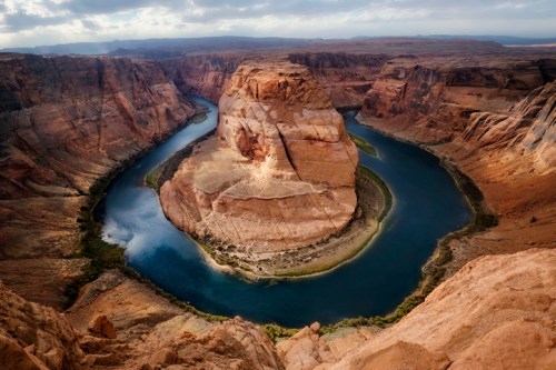 Aerial view of Horseshoe Bend, showcasing a winding river surrounded by steep canyon walls and rocky formations.