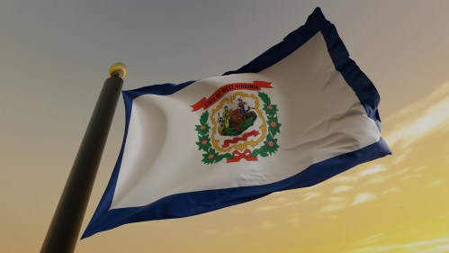 West Virginia state flag waving against a sunset background, featuring the state seal and a blue border.