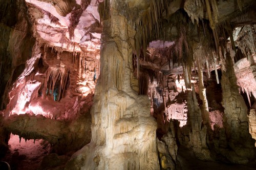 A stunning cave interior featuring stalactites and stalagmites, illuminated by colorful lights.
