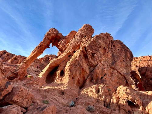 A striking rock formation with arches and holes, set against a clear blue sky in a desert landscape.