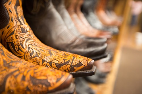 Close-up of intricately designed cowboy boots in a row, showcasing detailed leatherwork and various colors.