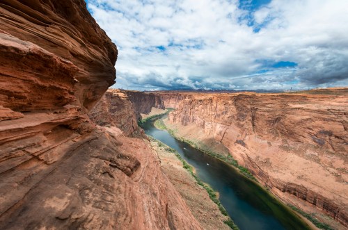 A winding river flows through a dramatic canyon landscape under a cloudy sky.