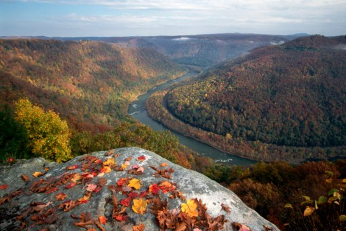 A scenic view of a winding river surrounded by colorful autumn foliage and rocky terrain.