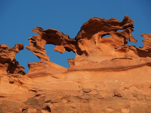 Unique rock formations with intricate shapes against a clear blue sky.