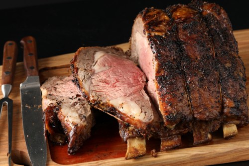 A beautifully cooked roast beef on a wooden cutting board, sliced to reveal its juicy pink interior.