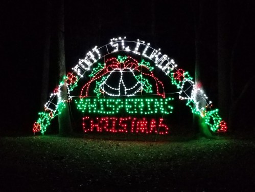 Colorful Christmas lights form an arch with "White Bear's Christmas" and festive decorations in a dark setting.