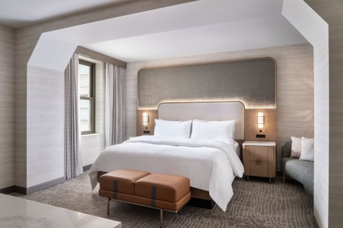 Modern hotel bedroom featuring a large bed, stylish decor, and natural light from a window.