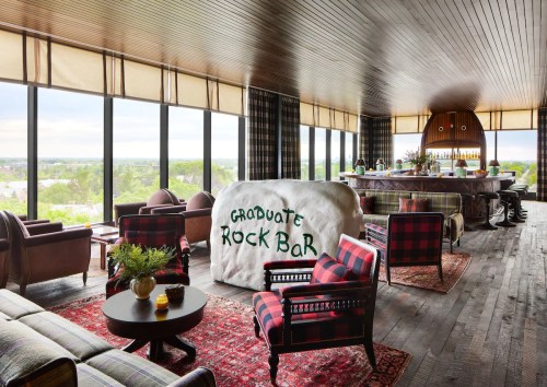 A stylish bar with large windows, featuring cozy seating, a rock bar centerpiece, and a scenic view.