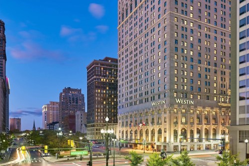 A cityscape at dusk featuring the Westin hotel, with busy streets and illuminated buildings in the background.
