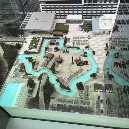 Aerial view of a resort-style pool area with winding water features, lounge chairs, and landscaped spaces.
