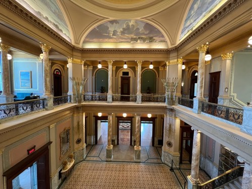 Interior view of a grand hall with ornate columns, decorative ceilings, and elegant lighting.