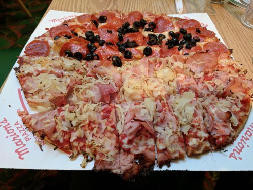 A large pizza divided into two halves: one with pepperoni and olives, the other with ham and sauerkraut.