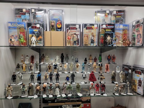 A display case filled with various Star Wars action figures and collectibles, arranged neatly on shelves.
