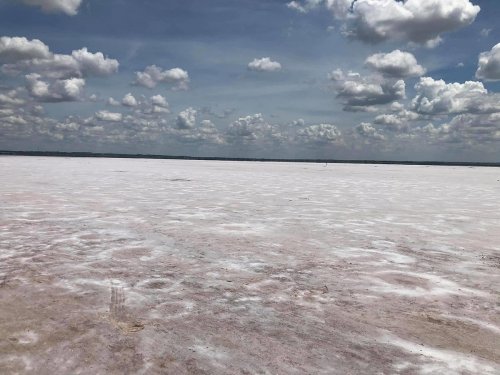 A vast, flat landscape covered in white salt, under a blue sky with fluffy clouds.