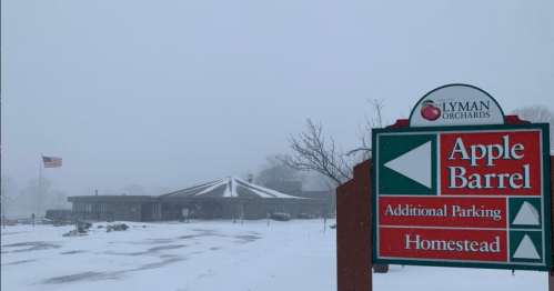 Snowy scene at Lyman Orchards with a sign for the Apple Barrel and additional parking. Flag visible in the background.