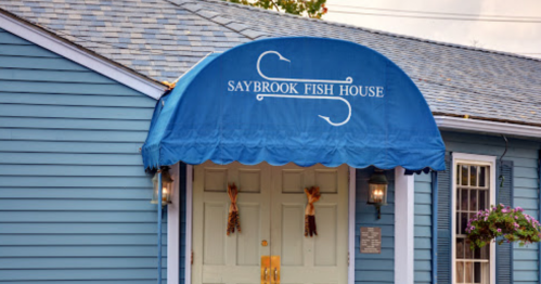 Blue building entrance with a blue awning reading "Saybrook Fish House" and decorative elements on the doors.