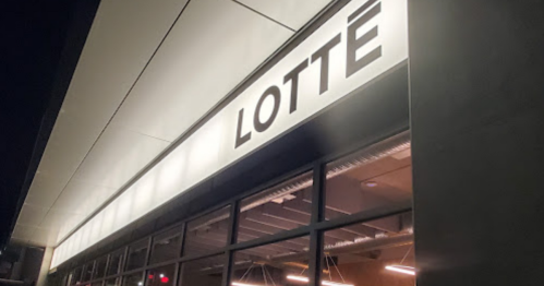 Illuminated sign for "LOTTE" on a modern building at night.