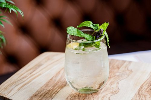 A refreshing cocktail with mint and lemon, served in a clear glass on a wooden table.