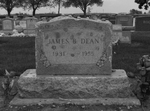 Gravestone of James B. Dean, 1931-1955, surrounded by grass and trees in a cemetery.
