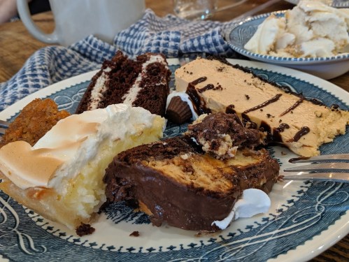 A plate with various desserts: chocolate cake, peanut butter pie, coconut cream pie, and a slice of chocolate cake.