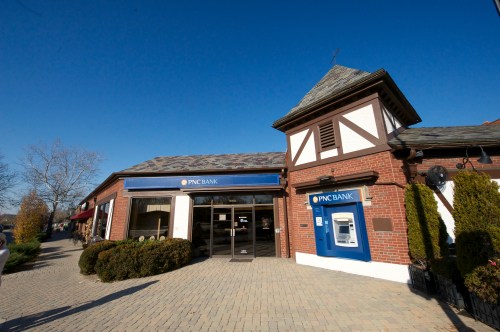 A PNC Bank branch with a distinctive architectural style, featuring a stone facade and an ATM outside.
