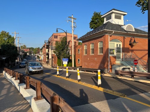 A street scene featuring a brick building, cars, and traffic signs under a clear blue sky.