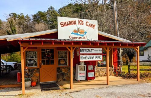A quaint café with a sign reading "Sharon K's Café" and a welcoming entrance, surrounded by trees.