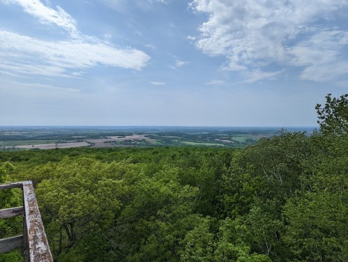 A panoramic view of lush green hills and fields under a partly cloudy sky.