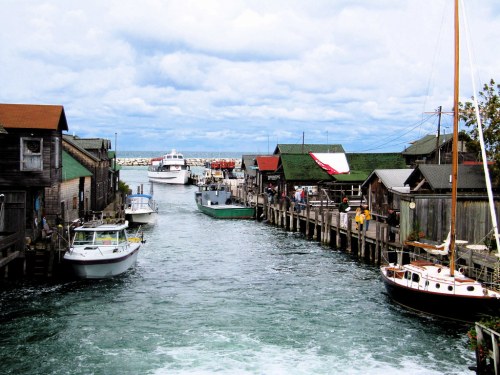 A scenic harbor with boats, wooden buildings, and a cloudy sky, creating a charming waterfront atmosphere.